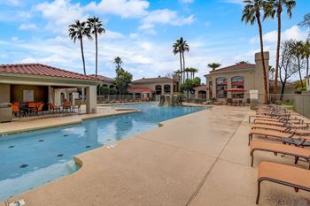 A pool surrounded by palm trees and sun loungers.